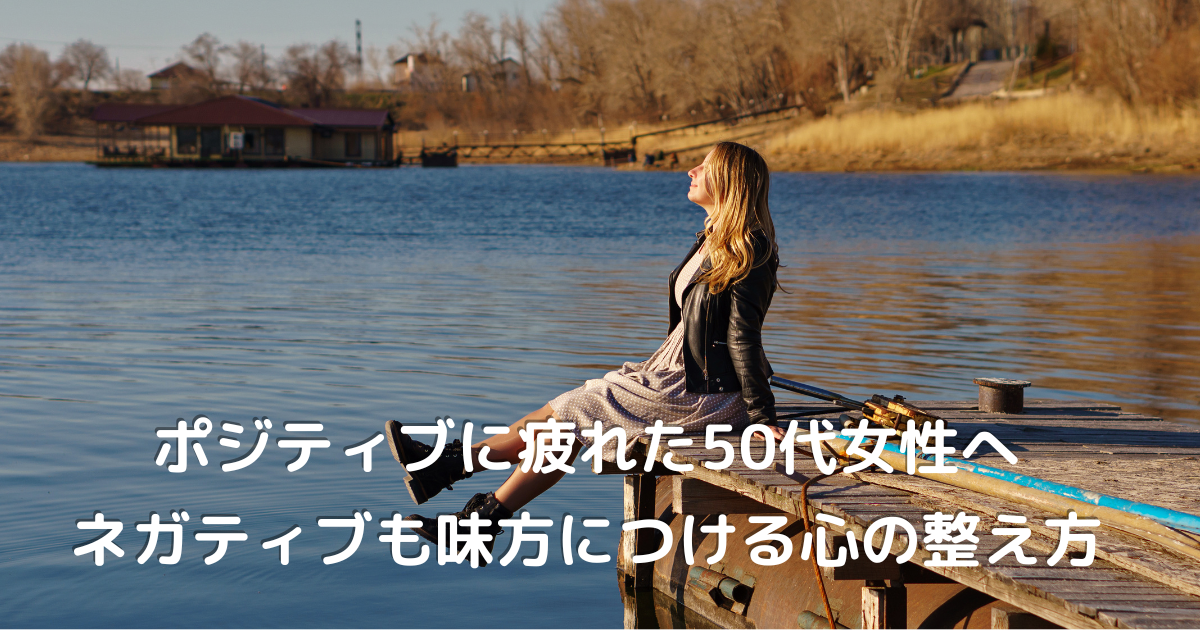 水辺で一人微笑む50代女性が、自分らしい人生を楽しむ様子の写真