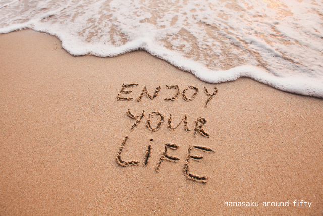 波打ち際の砂浜に「ENJOY YOUR LIFE」と書かれた文字。優しく寄せては返す波とともに、心にやすらぎを届ける風景。