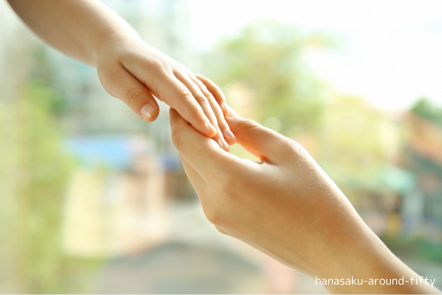 子どもの手と大人の手がやさしく重なり合う。親子のつながりと信頼を感じる画像。
